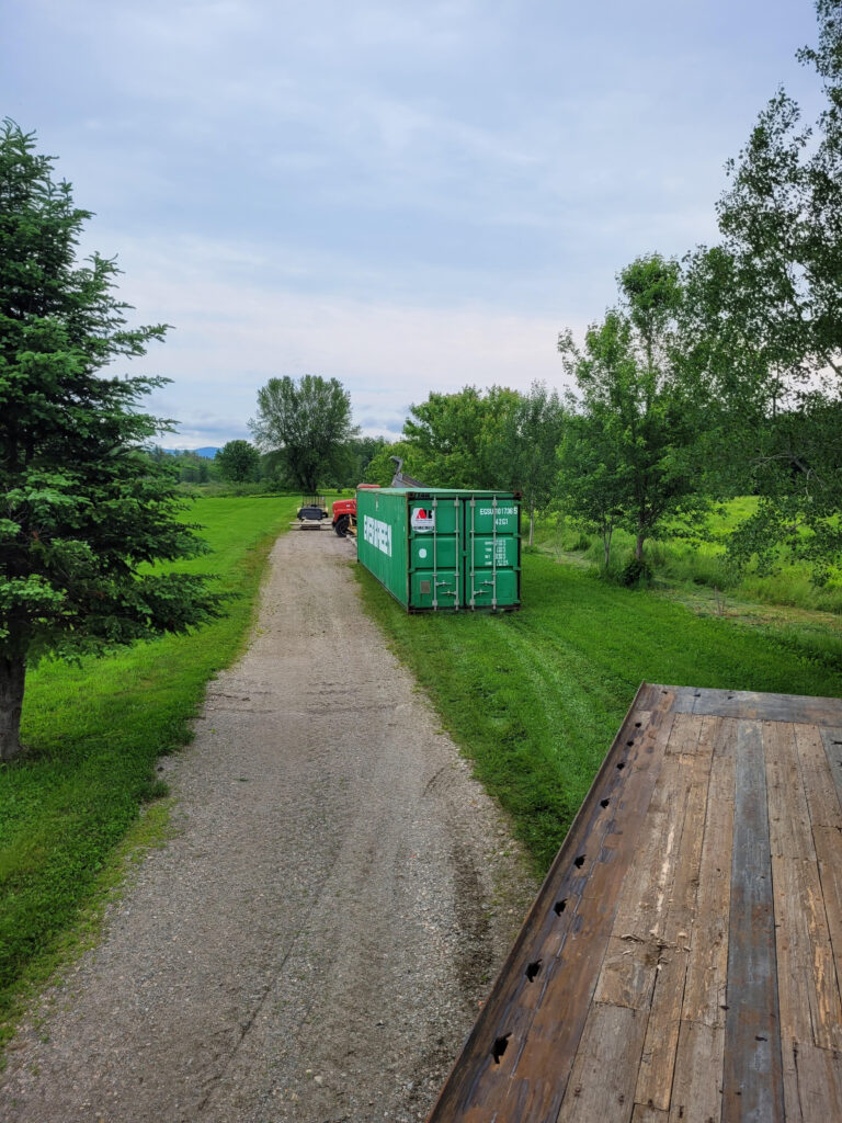 40 ft storage container placed along a gravel path in a rural setting, likely in Fryeburg, Maine 